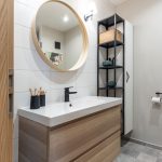 kúpeľňa s bielym obkladom, vzorovanou podlahou, závesnou poličkou s umývadlom a kovovým otvoreným regálom