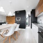 moderný otvorený priestor kuchyne, jedálne a obývačka ladený do antracitovej, sivej, bielej farby v kombinácii s drevom
