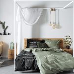 Spálňa s drevenou posteľou a obliečkami v čiernej a zelenej farbe