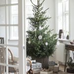 Vidiecky interiér so živým vianočným stromčekom s jednoduchými papierovými ozdobami
