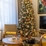 detail obývačky s retro halabala kreslami, okrúhlym stolíkom a lesklým stolíkom v štýle art deco, v pozadí je vianočný stromček tiež v štýle art deco