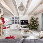 obývačka v modernom vidieckom štýle so sivou sedačkou a bielym preskleným stolíkom, po ľavej strane je piecka vsadená do priestoru na kozub, rímsa je sviatočne zdobená čečinou, pri televízii je vianočný živý stromček, na strope sú priznané drevené trámy
