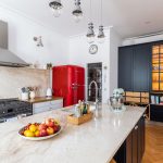 Moderná kuchyňa s červenou chladničkou, špajzou a čiernou presklenou skrinkou s pohármi a vínotékou