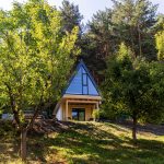 zmodernizovaná záhradná chatka s presklenou stenou pod štítovou strechou, obklopená prírodou