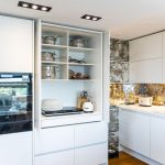 moderná biela kuchyňa s tzv. antickým zrkadlom, ako zástenou, ktorého autorkou je majiteľka bytu