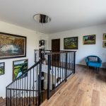 otvorený priestor schodiska v rodinnom dome, s kresielkami a obrazmi na stenách