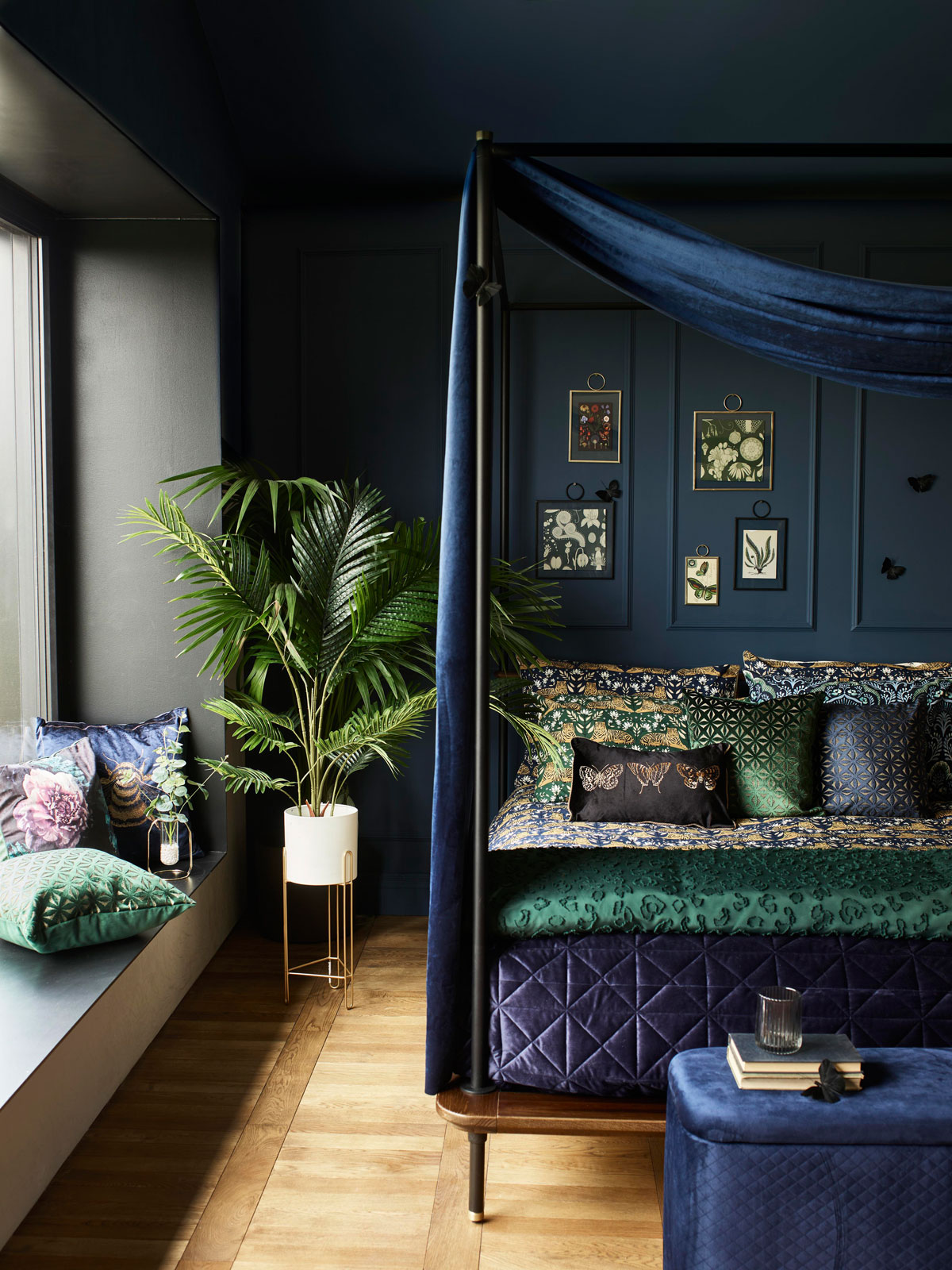 Luxusná spálňa v tmavých farbách modrej a zelenej, posteľ má zamatový baldachýn