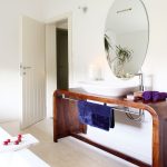Kúpeľňa v elegantnom prevedení s okrúhlym zrkadlom a oblým stolom s umývadlom