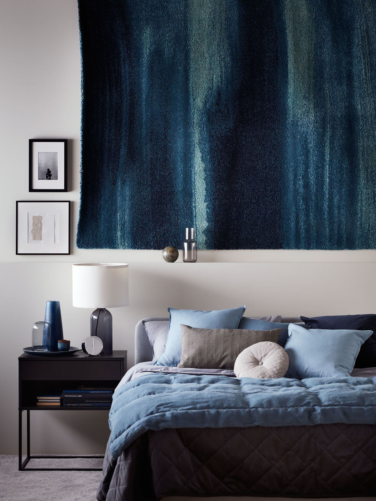 spálňa v modrej farbe s kobercom zaveseným nad posteľou
