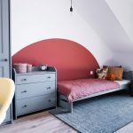 detská izba so sivou skriňou, komodou a posteľou, na stene pri posteli je namaľovaný červený polkruh