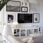 Biela obývačka v modernom vidieckom štýle, okolo TV sú povešané obrazy