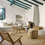 Jednoduchá prírodná vidiecka obývačka v bielej v kombinácii s hnedou na prírodných materiáloch a s akcentom na modrých stropných trámoch