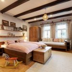 vidiecka spálňa na chalupe v tradičnom štýle, nábytky vrátane postele sú zo smrekového dreva, na strope sú priznané drevené trámy obložené sadrokartónom ktorý izbu presvetlí