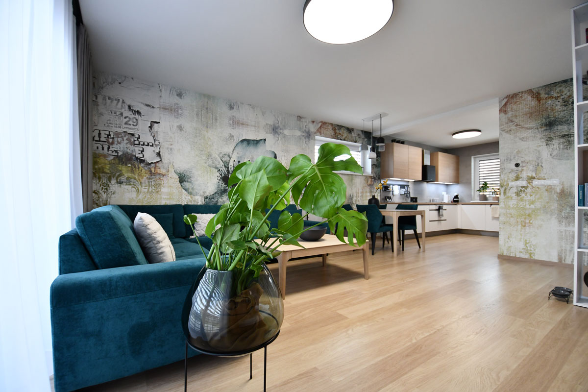 Spojená moderná obývačka s kuchyňou s výraznými tapetami a modrou sedačkou