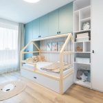 chlapčenská izba s modrými a bielymi skrinkami a posteľou v tvare domčeka