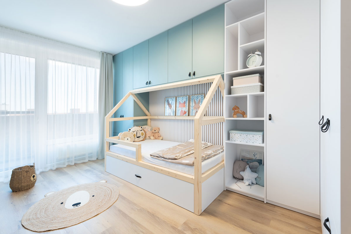 chlapčenská izba s modrými a bielymi skrinkami a posteľou v tvare domčeka