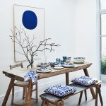Rustikálny drevený stôl s lavicou s modrými podsedákmi a obrazom s modrým kruhom