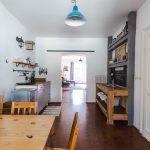 vidiecka retro kuchyňa v historickom byte s jedálenským kútom, jednoduchou kuchynskou linkou a samostatným drezom vsadeným do dreveného stola, v kuchyni je zrenovovaná tmavá drevená podlaha