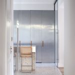 pohľad do modernej minimalistickej kuchyne s antikorovými dvermi, ktoré ukrývajú kuchynskú linku
