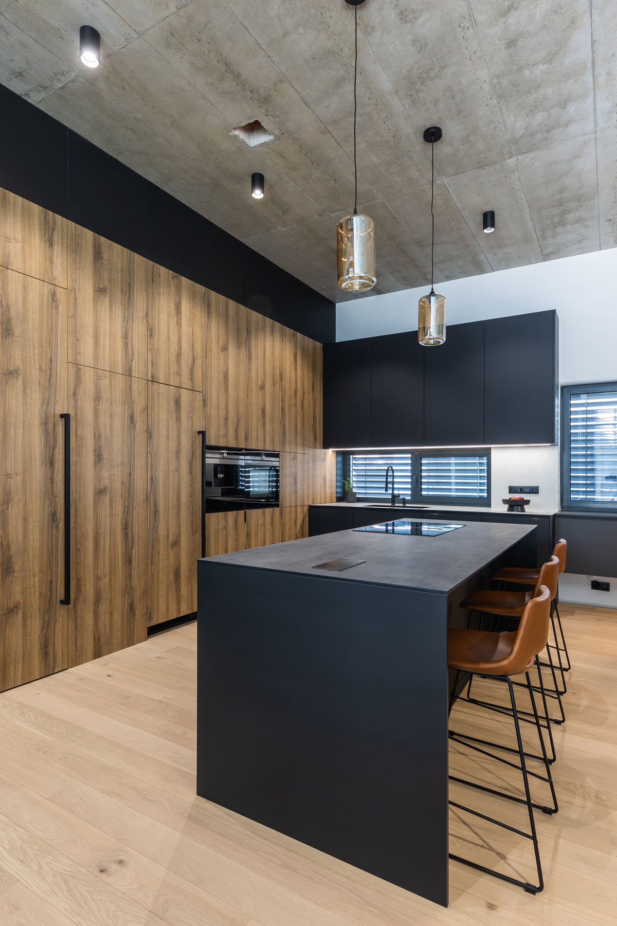 moderná minimalistická kuchyňa v kombinácii dreva a čiernej farby s ostrovčekom a betónovým stropom