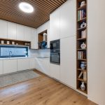 biela kuchyňa s drevenými policami a lamelovým stropom