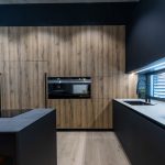 moderná kuchyňa v minimalistickom dizajne s kuchynskou linkou bez úchytiek, v kombinácii dreva a čiernej farby