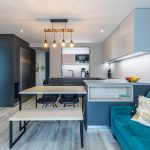 spojená obývačka s kuchyňou s modrou sedačkou a antracitovo-sivou kuchynskou linkou v minimalistickom štýle
