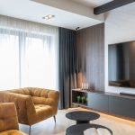 elegantná obývačka s polstrovanou horčicovou sedačkou a tmavým dreveným nábytkom