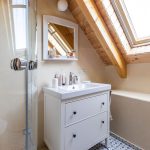 jednoduchá biela podkrovná kúpeľňa s vidieckou vzorovanou podlahou a hlinenými omietkami