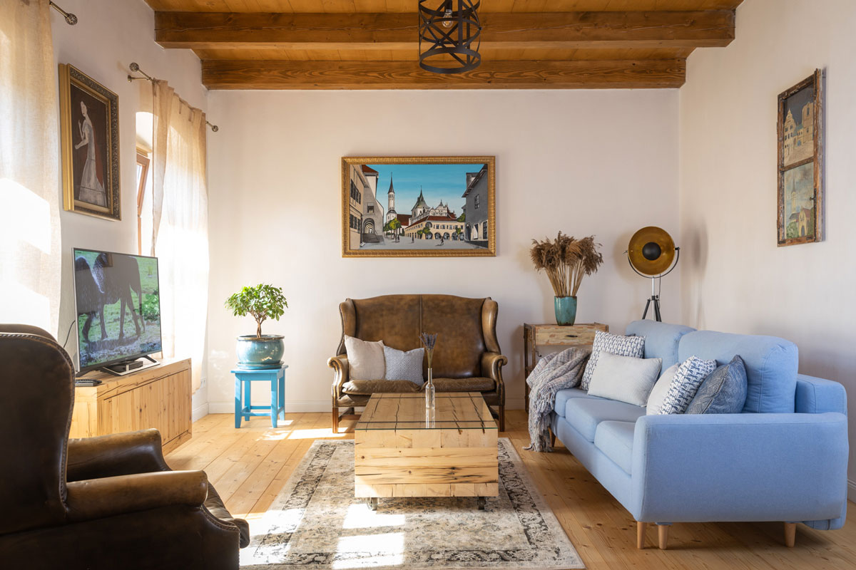 obývačka s modernou modrou sedačkou a starožitnými koženými kreslami