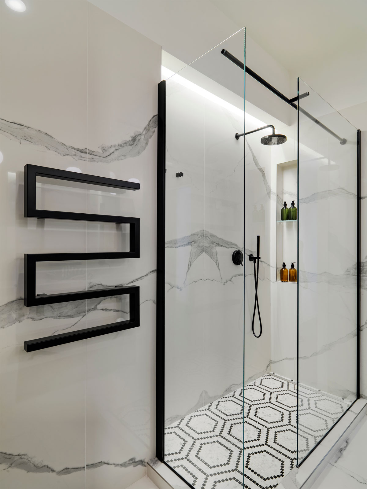 Kúpeľňa so sprchovým kútom a čiernym rebríkovým radiátorom v tvare dvojitého S