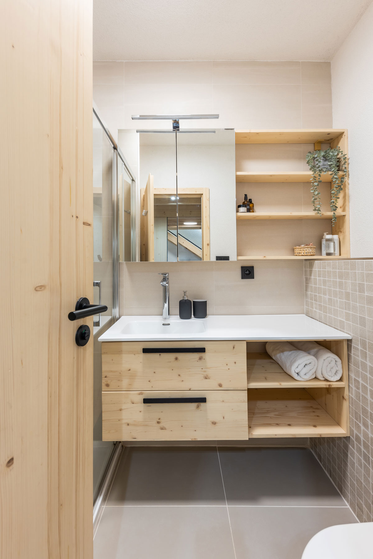 kúpeľňa s dreveným nábytkom a umývadlom s odkladacím miestom, ktoré je cez celú skrinku