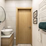 Malá kúpeľňa so svetlým obkladom, dreveným nábytkom a bielym rebríkovým radiátorom